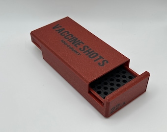 May include: A red plastic box with a sliding drawer that says "VACCINE SHOTS 100 COUNT" on the top. The drawer is open and reveals a black grid with small holes. The box is labeled "22 LR" on the bottom.