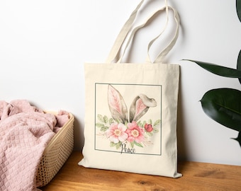 May include: A beige tote bag with a floral design featuring a bunny's ears and the word "Peace".