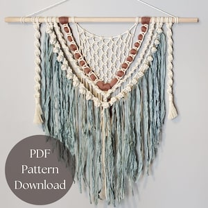 May include: A macrame wall hanging with a wooden dowel, featuring cream-colored knotted netting, teal fringe, and brown beads. The design includes a cream-colored fringe and a circular graphic with the text "PDF Pattern Download".