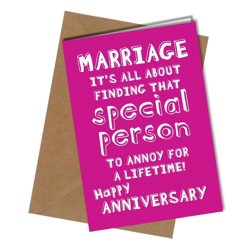 May include: A magenta anniversary card with white text that reads "MARRIAGE IT'S ALL ABOUT FINDING THAT special person TO ANNOY FOR A LIFETIME! Happy ANNIVERSARY" is displayed on top of a brown envelope.
