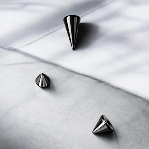 May include: Three black metal cone-shaped studs of varying sizes.