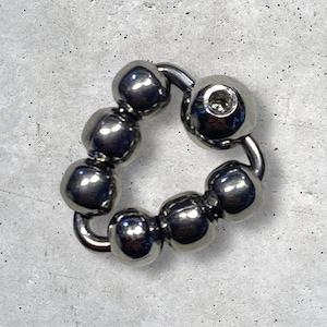 May include: A shiny, silver-colored captive bead ring. The ring features a series of rounded beads connected by curved metal segments. The design is circular, with a single bead containing a small screw.