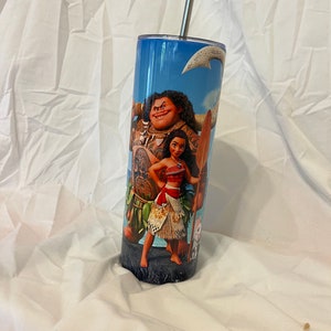 K&ouml;nnte beinhalten: Ein Edelstahlbecher mit blauem Hintergrund und einem Motiv von Maui und Moana aus dem Disney-Film Vaiana. Der Becher hat einen Strohhalm.