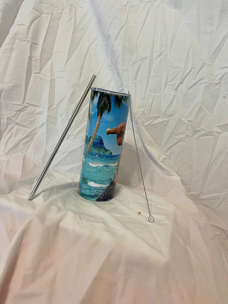 K&ouml;nnte beinhalten: Ein Edelstahlbecher mit einem tropischen Inselmotiv. Der Becher wird mit einem Edelstahlstrohhalm und einer Reinigungsb&uuml;rste geliefert.