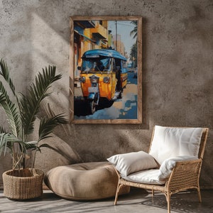 Puede incluir: Una pintura enmarcada de un auto-rickshaw amarillo y azul conduciendo por una calle de una ciudad. El rickshaw está enfocado y el fondo está desenfocado. La pintura está en un marco de madera.