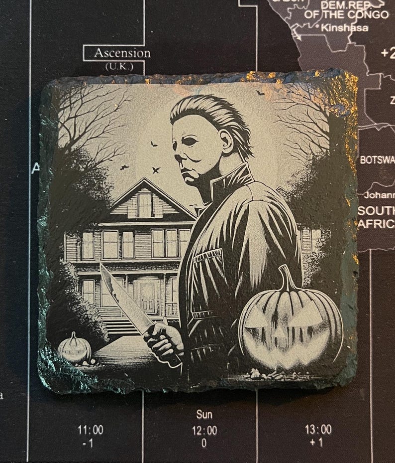 May include: Black and white illustration of a man wearing a jacket and holding a knife. He is standing in front of a house with a jack-o-lantern in the foreground. The image is on a black slate coaster.