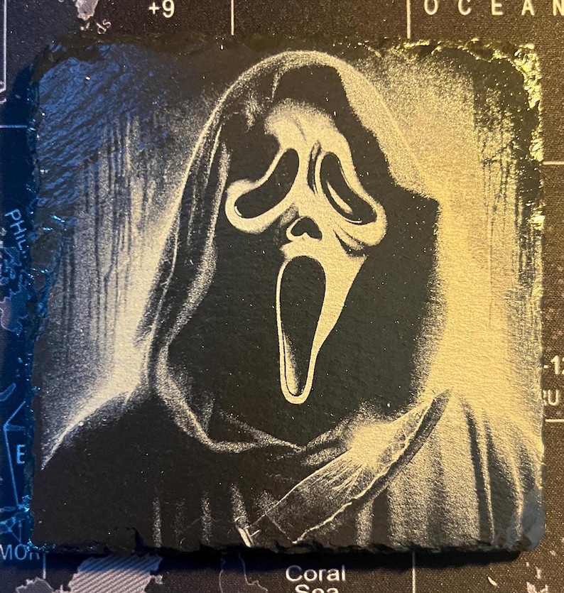 May include: A black and white image of the Ghostface character from the Scream movie franchise. The character is wearing a white mask with a scream face and a black hooded robe. The character is holding a knife in their right hand.