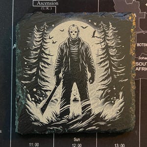 May include: Black and white illustration of a horror movie character holding a machete in a dark forest setting. The character is wearing a hockey mask and has a menacing expression.