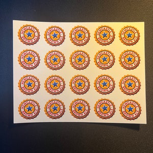 May include: Twenty-five round stickers with a gold background and red and blue accents. The stickers feature the text "Newcastle Brown Ale" and a star.