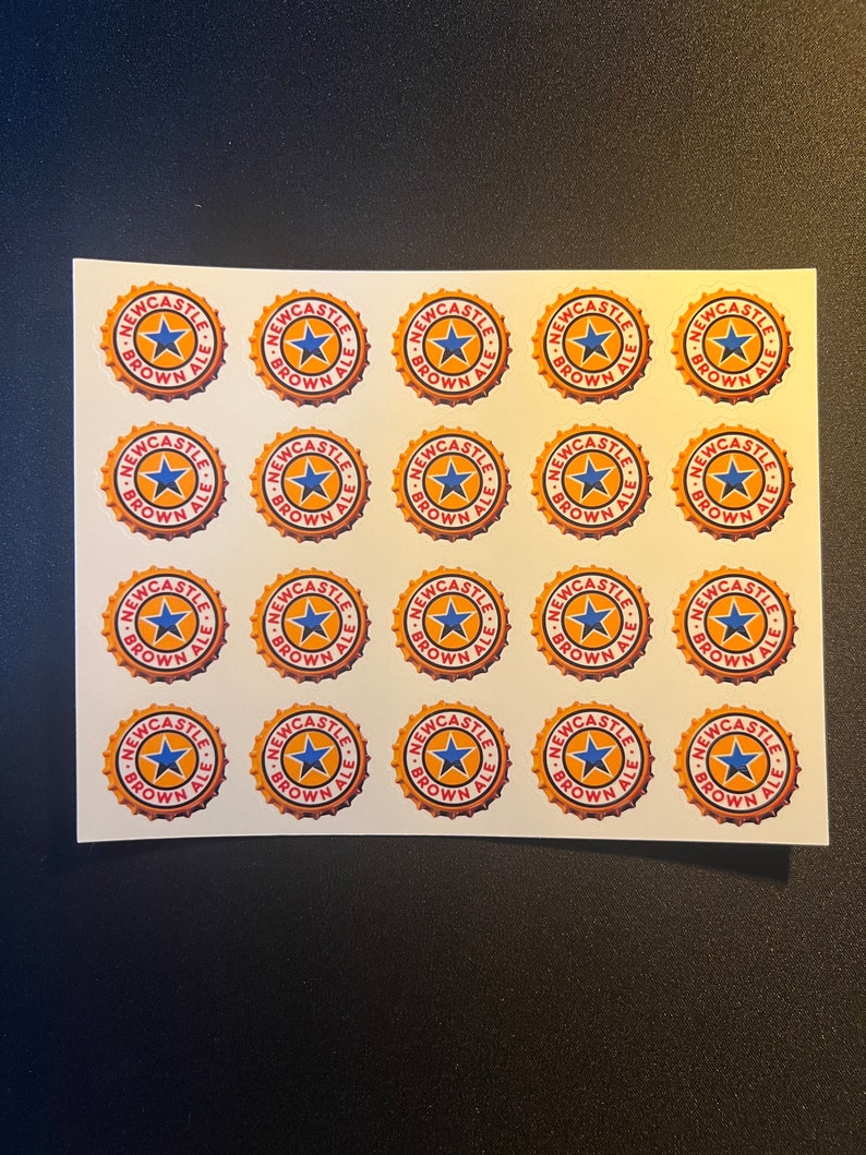 May include: Twenty-five round stickers with a gold background and red and blue accents. The stickers feature the text "Newcastle Brown Ale" and a star.
