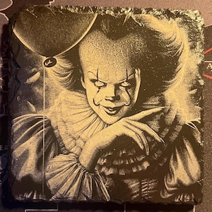 May include: Black and white illustration of Pennywise the Dancing Clown from the movie IT. The clown is wearing a ruffled collar and has a sinister smile. A red balloon is floating above the clown's head.