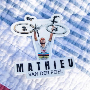 Może przedstawiać: Biała naklejka z czarno-białym obrazkiem kolarza trzymającego rower nad głową. Naklejka zawiera napis "MATHIEU VAN DER POEL" czarnymi literami.
