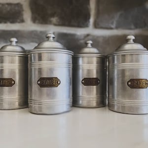 Peut inclure: Quatre boîtes en argent avec des étiquettes en laiton. Les étiquettes indiquent "Pâtes", "Chicoree", "Pâtes" et "O.Café".