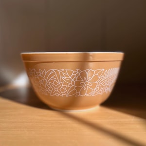 Peut inclure: Un bol mélangeur en céramique brun avec un motif floral blanc. Le bol est posé sur une surface en bois.