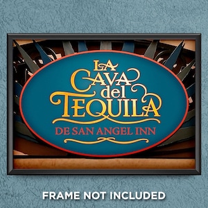 May include: A framed sign with the text "LA CAVA del TEQUILA DE SAN ANGEL INN" in gold lettering on a teal oval. The sign has a red border and is set against a dark background.