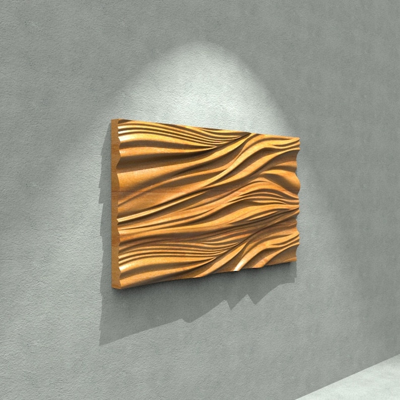 May include: A rectangular wooden wall art piece with a wave-like pattern carved into its surface. The artwork is a warm, natural wood tone, mounted on a gray wall. The piece is illuminated by a spotlight, creating shadows that emphasize the texture.