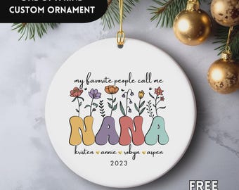 May include: White ceramic ornament with the text "my favorite people call me NANA" in colorful letters. The ornament features floral designs and the names of family members. The year 2023 is also included. The text "ONE OF A KIND CUSTOM ORNAMENT" is at the top.