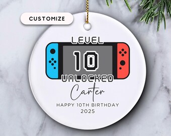 May include: White ceramic ornament with a video game controller design. The ornament features the text "LEVEL 10 UNLOCKED" and "Carter", with "HAPPY 10TH BIRTHDAY 2025" below. A gold string is attached for hanging.