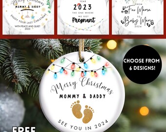 May include: White ceramic Christmas ornament with the text "Merry Christmas Mommy & Daddy See You in 2024" and gold footprints. The ornament is decorated with colorful lights and a string for hanging. The image also shows other ornament designs.