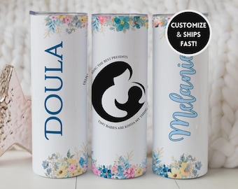 Può includere: Bicchiere termico bianco con decorazioni floreali e la parola "DOULA" in blu. Un altro bicchiere presenta una grafica in bianco e nero di una madre e un bambino, con il testo "DELIVERING THE BEST PRESENTS. TINY BABIES ARE KINDA MY THING." Un terzo bicchiere ha il nome "Melanie".