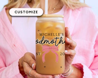 May include: A frosted glass beverage container with a bamboo lid and a straw. The container is filled with a light brown liquid and features the text "MICHELLE'S godmother" with a pink bow graphic. The word "CUSTOMIZE" is in a white box.