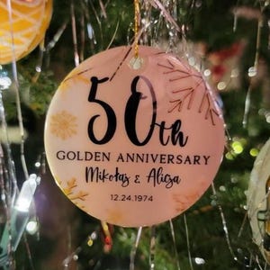 May include: A pink and gold round Christmas ornament with the text "50th Golden Anniversary Mikołaj & Alicja 12.24.1974".