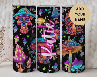 May include: A black tumbler with a colorful mushroom design. The design features various mushrooms in shades of blue, orange, purple, and yellow, with the name "Katie" in a cursive font. The background is filled with stars and smaller mushroom shapes.