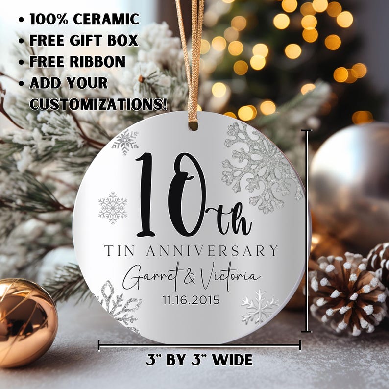 May include: A white ceramic ornament with a silver glitter design. It features the text "10th Tin Anniversary Garret & Victoria 11.16.2015" and is 3 inches wide.