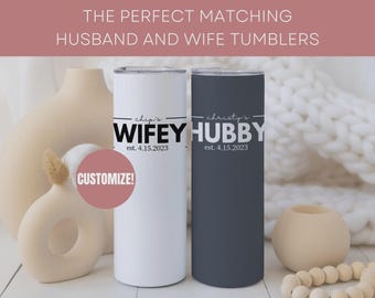 Può includere: Due bicchieri cilindrici, uno bianco e uno grigio scuro, con le parole "Wifey" e "Hubby" in nero. I bicchieri hanno il testo "est. 4.15.2023". L'immagine include il testo "THE PERFECT MATCHING HUSBAND AND WIFE TUMBLERS" e "CUSTOMIZE!"