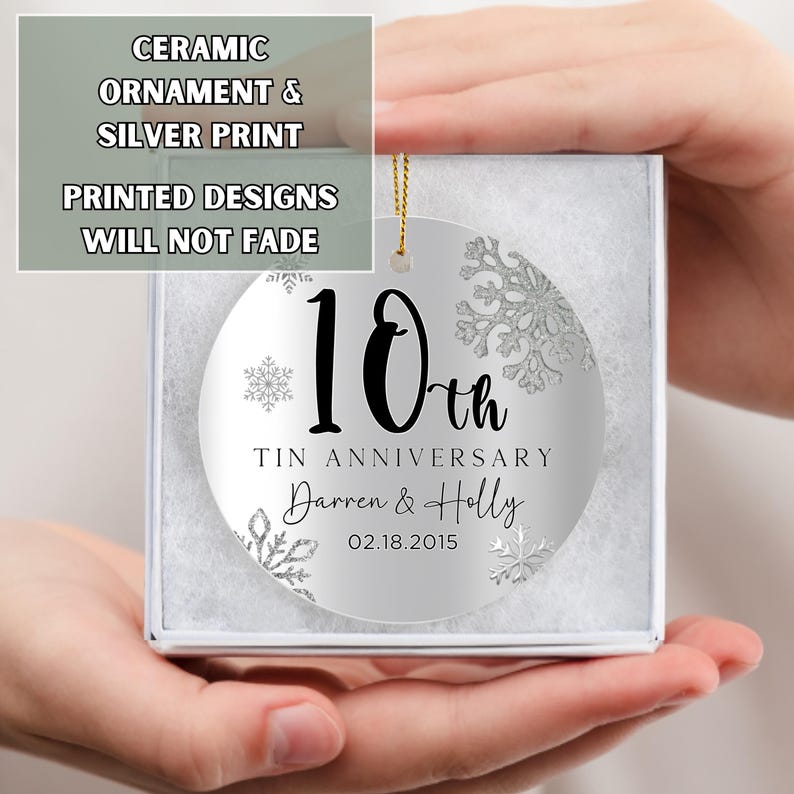 May include: A silver ceramic ornament with a white snowflake design. The ornament is personalized with the text "10th Tin Anniversary Darren & Holly 02.18.2015".