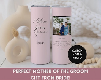 May include: A pink tumbler with the words "Mother of the Groom" and the date 5.15.2024. The other side features a photo and a custom note. The tumbler is a gift from the bride.