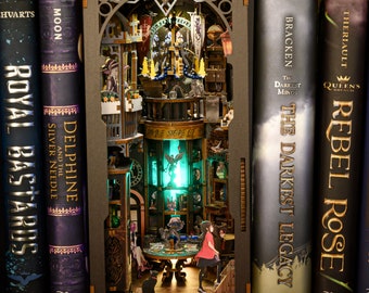 Może przedstawiać: Szczegółowa, podświetlana diorama w rogu książki przedstawiająca scenę fantasy z miniaturowymi figurkami, meblami i elementami architektonicznymi. Róg książki znajduje się pomiędzy kilkoma książkami w twardej oprawie.