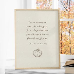 May include: A beige framed print with a quote from Galatians 6:9, "Let us not become weary in doing good, for at the proper time we will reap a harvest if we do not give up." The print features a simple line drawing of a pumpkin.
