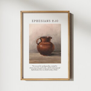 Puede incluir: Una impresión enmarcada con una pintura de acuarela de una jarra de barro marrón sobre una mesa de madera. La impresión incluye el texto "EPHESIANS 2:10" y una cita del versículo bíblico: "Porque somos hechura suya, creados en Cristo Jesús para buenas obras, las cuales Dios preparó de antemano para que anduviésemos en ellas."