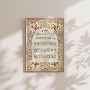 Puede incluir: Impresión enmarcada con el texto "The Beatitudes" en una fuente decorativa. La impresión tiene un fondo beige con patrones florales y de hojas en tonos verdes, naranjas y marrones. El marco es de color marrón claro.