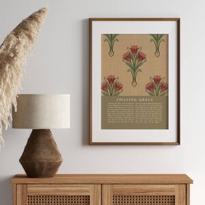 May include: A framed wall art print featuring a repeating pattern of red tulips with green stems on a textured tan background. Below the floral design, the text Amazing Grace is printed in a serif font, followed by the full lyrics of the hymn.