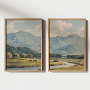 May include: Two framed landscape art prints. Each print features a pastoral scene with mountains, trees, and a river. The prints have a vintage aesthetic and include white text with a religious quote.