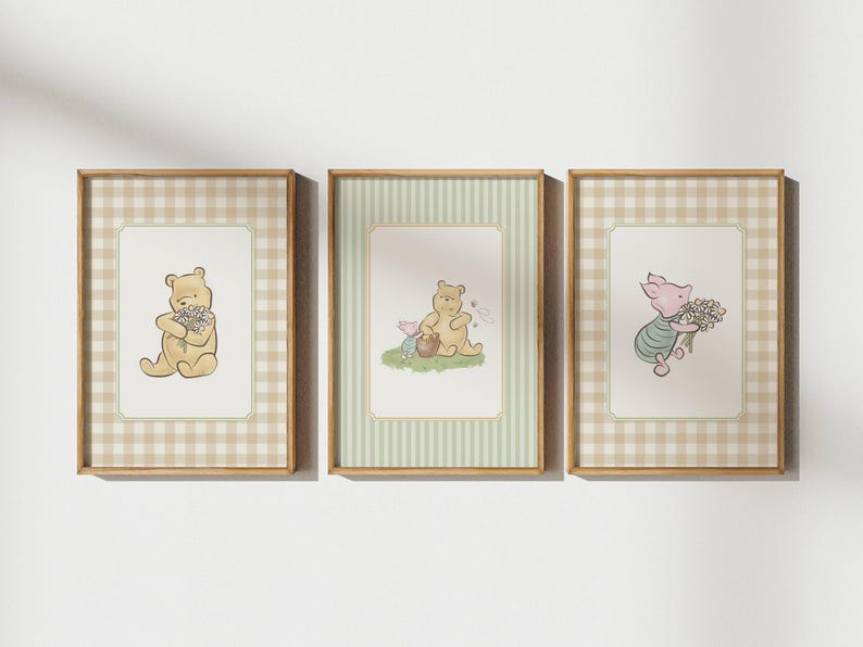 May include: Three framed prints featuring Winnie the Pooh characters. Each print has a light brown wooden frame. The first print shows Pooh holding flowers, the second shows Pooh and Piglet, and the third shows Piglet holding flowers. The background has a gingham or striped pattern.