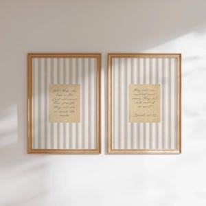 May include: Two framed prints with a light wood finish. Each print features a beige background with vertical gray stripes. A square, aged paper with handwritten text is centered on each print. The text is a religious quote.