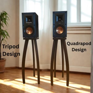 May include: Two black bookshelf speakers with copper-colored woofers, each mounted on a dark wooden stand. The left stand features a three-legged tripod design, while the right stand features a four-legged quadrapod design with text labels.