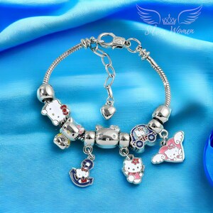 May include: Silver charm bracelet with Hello Kitty themed charms, including a car, a heart, an anchor, and a Hello Kitty figure. The bracelet has a silver clasp.