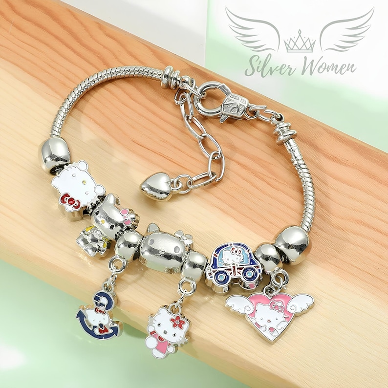 May include: A silver charm bracelet with a variety of colorful Hello Kitty charms, including a heart, a car, and an anchor. The bracelet is made of a snake chain and has a lobster clasp.