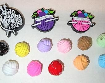 May include: A collection of colorful crochet-themed charms and embellishments. Includes charms with the text "NO mistakes, happy little accidents" and "CROCHET ALL DAY". Also shown are various yarn ball charms in multiple colors.