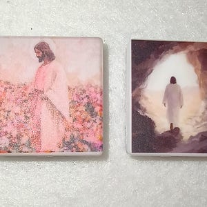 May include: Two rectangular religious art pieces. One depicts a figure in white robes standing in a field of pink flowers. The other shows a figure in white robes walking towards a bright light.