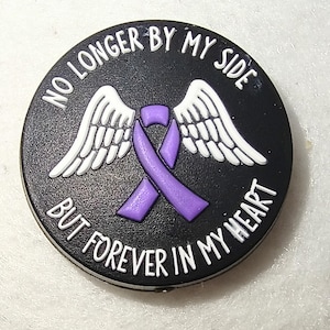 May include: A black, round memorial pin with white text that reads "NO LONGER BY MY SIDE BUT FOREVER IN MY HEART." The pin features white angel wings and a purple awareness ribbon.