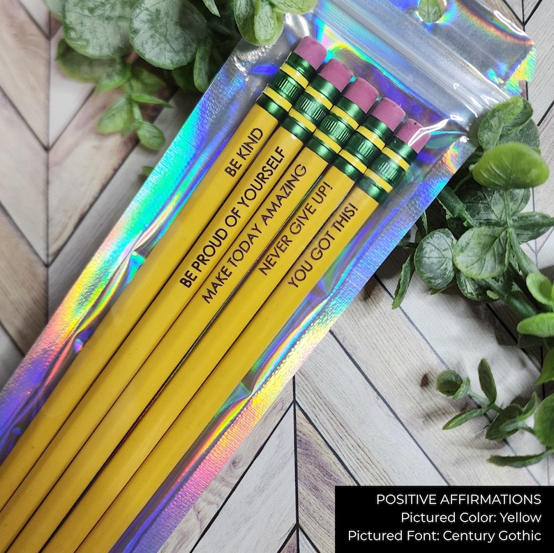 May include: A pack of yellow pencils with pink erasers, each printed with a positive affirmation in black. The pencils are contained in a clear, iridescent cellophane bag. Affirmations include "BE KIND" and "YOU GOT THIS!"