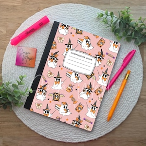 May include: A composition book with a light pink cover featuring a repeating pattern of white ghosts wearing witch hats, reading books, and holding orange bows, alongside a pink Sharpie, a pink pen, an orange pencil, and a square logo card.