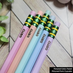 May include: Five pastel-coloured pencils, each inscribed with the name "HARPER". The pencils feature green and yellow detailing near the eraser. The colours include pink, peach, blue, and lavender.