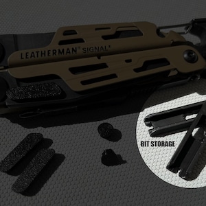 Puede incluir: Una herramienta multifunción Leatherman Signal en negro mate y verde oliva con mosquetón, acompañada de dos pequeñas almohadillas negras texturizadas, dos pequeños componentes circulares negros y un accesorio de almacenamiento de puntas con la etiqueta BIT STORAGE.