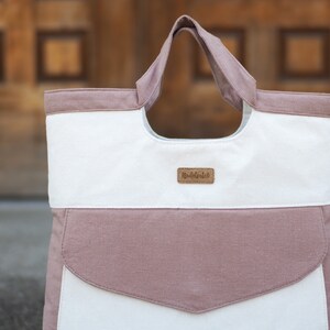 May include: A white and pink canvas tote bag with a brown leather label that says "remarkable".